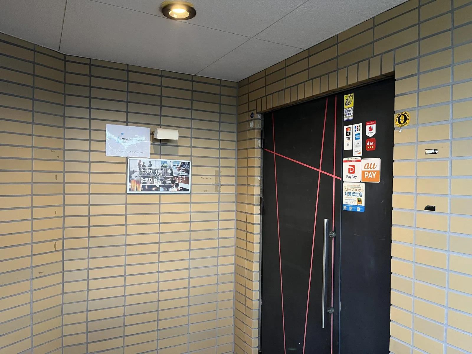 黒い扉に赤いラインが入った、3階のたまりBar入口